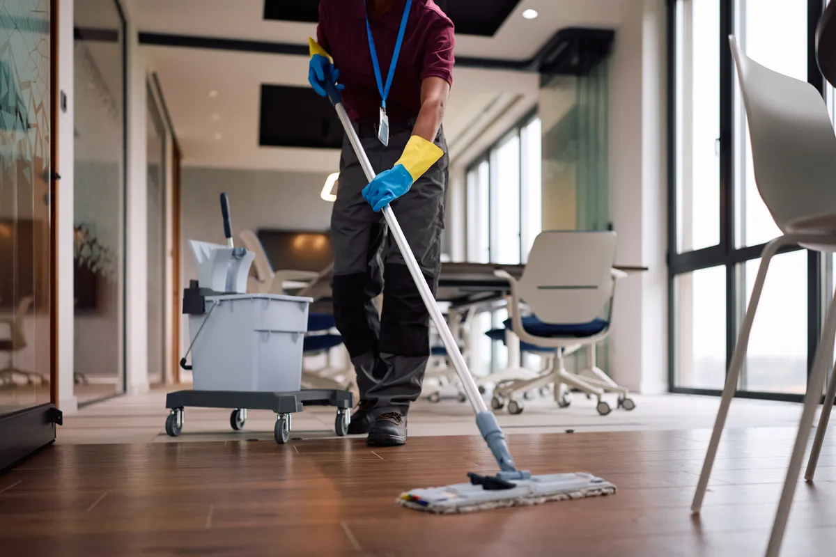 A cleaner mopping the floor of a bright, modern office