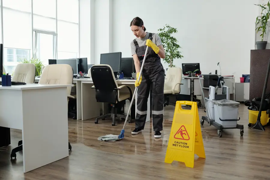 A cleaner in workwear mopping a commercial floor